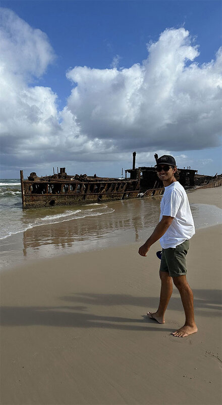 Eine lächelnder Mann steht an einem Sandstrand in Sydney. | © Bastian Ortner