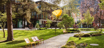 Grüner Park mit Wegen, bunten Sitzbänken und auffälligen gelben Lampen vor der FH Kufstein Tirol | © FH Kufstein Tirol